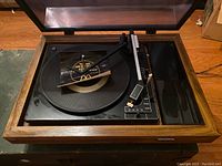 Top view of BSR record player showing turntable, tonearm, speed settings, and wood casing with dust cover open.