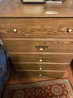 Chest of drawers shown from the front with visible carved detail and varied drawer knobs and handles.