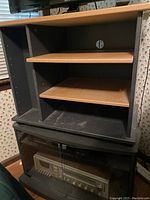 Front view of the entertainment center showing two wooden shelves in the upper section and a lower cabinet with glass doors housing a stereo receiver (stereo not included).