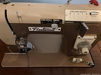 Close-up of Fleetwood sewing machine head showing manual stitch controls and zigzag width selector.