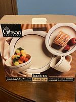 Box showing the complete Gibson stoneware 16-piece set branding and image of the plate, mug, bowl, and side plate.