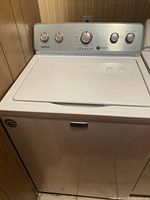 Maytag top load washing machine with white finish and metal control panel featuring dials.