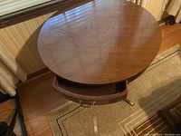 Top down view of round wooden table showing drawer open and surface condition