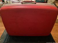 Exterior view of red Samsonite hard shell train case showing surface wear and scratches
