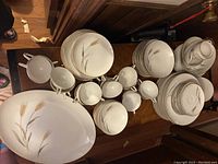 Top down view of the full dinnerware set spread out on a table including plates, bowls, cups, platters and serving pieces showing the pattern and quantity.