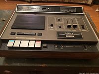 Front and top view of the Sony TC-165 cassette player showing control panel, buttons, and audio level meters.