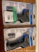 Two sealed Mastercraft infrared thermometer repair kits in original packaging lying on a wooden surface. Each kit includes a battery shown through clear plastic and features blue and black tool body.