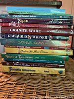 Photo of 14 assorted antiquing books stacked showing titles related to pottery, glass, and dinnerware collectibles