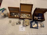 Photo of three wooden boxes, various coins, plastic coin holders, plastic bags, and foreign banknotes.
