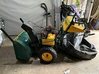 Side view showing overall machine, engine housing, wheels, chute and handlebars