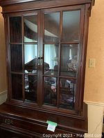 Full view of the upper section of the wooden hutch with glass doors and interior shelving visible through the glass.