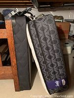 Photo of the twin mattress with visible patterned cover and brand tag leaning against a wooden bed frame.