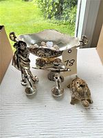 Front view of all items showing bowl, old man statue, dolphin, turtle, and vases arranged on white surface by window