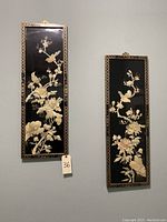 Photo of 2 Asian wall art frames with raised 3D gold floral and bird designs on black background