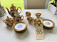 Full view of the tea and coffee set on table including cups, saucers, sugar bowl, coffee pot, and milk server with natural light