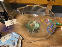 Top-down view showing ruffled-edge crystal platter and grape cluster silver base