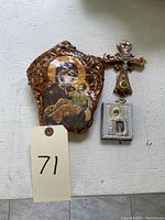 Three small religious artifacts including a hand-painted Virgin Mary icon on wood, a small embossed metal Virgin Mary icon, and a small metal cross with a colored stone.