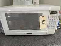 Front view of Panasonic inverter microwave oven showing keypad and door with tag 115