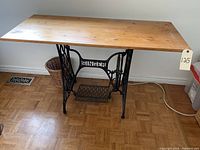 Front view of Singer sewing machine base table with wooden top on parquet floor.