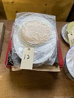 Two serving platters stacked; top one includes a bamboo plate covered in bubble wrap