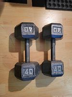 Top view of pair of 40 lb hex dumbbells showing cast iron heads with raised 40 lb markings painted white and blue highlights, and knurled steel handles.
