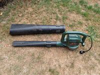 Black & Decker Super Vac blower and vacuum unit with two detachable black blower tubes on dry grass.