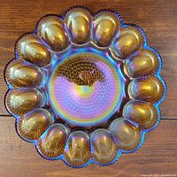 Top view of a carnival glass deviled egg serving dish featuring 12 egg-shaped compartments with iridescent color and scalloped edges.