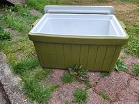 Open view of vintage Coleman cooler showing white insulated interior and olive green textured exterior body.