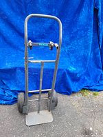 Front full view of the fridge dolly in upright 2-wheel dolly configuration showing the curved handle, frame, wheels and base plate.
