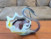 Front view of a decorative glass swan figurine placed on a wooden table.