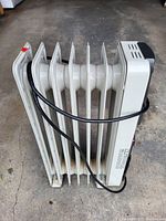 Side profile of a white Kenwood oil heater showing multiple heat fins and a black power cord wrapped around the unit.