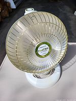 Front view of the Presto HeatDish parabolic electric heater showing the parabolic reflective dish with safety wire guard and off-white base.