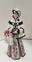 Front view of the porcelain lady figurine holding a bag of toys, showing detailed clothing patterns and facial features.