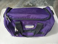 Purple travel bag showing the top and side with zipper closures and brand label "Voxodue".