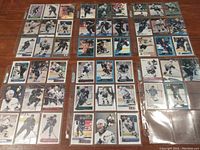 Full spread of 59 Vancouver Canucks hockey cards laid out in clear sleeves on a table. Variety of players mainly from the 1990s shown.