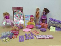 Three Barbie dolls, Barbie book, Barbie tea set with utensils and case, and temporary tattoo and sticker treats.