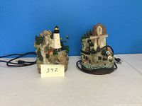 Photo showing two electric decorative water fountains side by side: a lighthouse and a windmill.