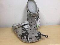 Pair of new Crocs camo pattern clogs with tags, size XXL shown from front and side angles