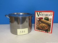 Large stainless steel stock pot with lid alongside the vegetarian cookbook.