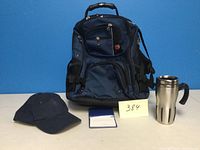 Swiss Army backpack with black hat and sticky notes placed in front on a flat surface against blue background