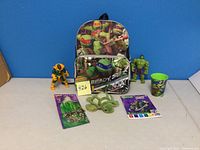 Photo showing all items in the lot: backpack, cup, magic paint poster book, on-the-go bottle, two action figures, and stuffed turtle toy.