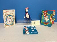Front view of three vintage Dr. Seuss books and a Cat in the Hat plush doll on display against blue backdrop.