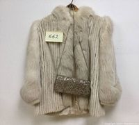 Front view of the light beige/cream women's fur coat with soft fur collar and cuffs, accompanied by the beaded purse hanging in front