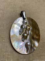 Close-up of the front of the pendant showing blister baroque pearls on a shiny mother-of-pearl base, with a silver bail attached at the top.