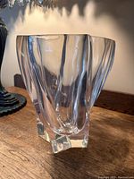 Front angled view of the clear Lucite vase showing the wavy sculpted vertical design and thick base.