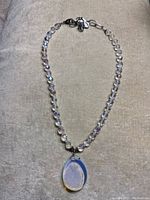 Full view of the necklace showing faceted clear crystal beads with a natural quartz teardrop pendant at the center.