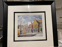 Full view of framed print showing street scene with multiple buildings, shadows, and sky