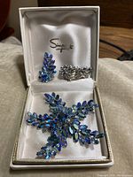 Vintage Sherman 3-piece jewellery set in original box. Brooch and matching earrings with blue aurora borealis rhinestones.