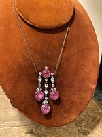 Full view of vintage silver-tone necklace displayed on a brown velvet bust. Features a pendant with large round pink rhinestones and smaller clear stones.