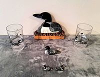 Lot items including wooden wall rack, two plastic drink glasses, vintage wooden carving, and earrings arranged on a grey surface